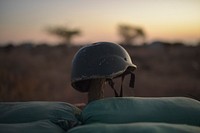 A soldier&#39;s helmet rests on a post above some sandbags at an army base in El Baraf, Somalia. Original public domain image from <a href="https://www.flickr.com/photos/au_unistphotostream/25136303759/" target="_blank">Flickr</a>
