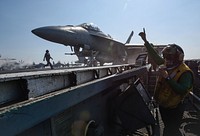 U.S. Navy Aviation Boatswain’s Mate (Equipment) 2nd Class Mariani Rivera signals that an aircraft is ready for launch on the flight deck of the aircraft carrier USS Theodore Roosevelt (CVN 71) in the Arabian Gulf Feb. 4, 2018.
