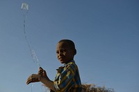 A boy flys his homemade kite at an IDP camp near the town of Beletweyne, Somalia, on May 28, 2016. Original public domain image from Flickr