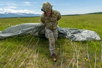 An Airman assigned to the 3rd Air Support Operations Squadron gathers up his parachute after conducting an airborne proficiency operation with Japan Ground Self-Defense Force Soldiers, and paratroopers assigned to the 4th Infantry Brigade Combat Team (Airborne), 25th Infantry Division, U.S. Army Alaska, on Malemute drop zone at Joint Base Elmendorf-Richardson, Alaska, June 13, 2018, during Exercise Arctic Aurora. Arctic Aurora is a bilateral training exercise involving elements of the Spartan Brigade and the JGSDF, which focuses on strengthening ties between the two by executing combined small unit airborne proficiency operations and basic small arms marksmanship. (U.S. Air Force photo by Justin Connaher). Original public domain image from Flickr