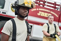 Fire protection specialist Airman 1st Class Brian Charles, a native of Ft. Lauderdale, Fla., assigned to the 673rd Civil Engineer Squadron, watches fellow Airmen gather water hoses after firefighter training on a simulated aircraft fire at Joint Base Elmendorf-Richardson, Alaska, Wednesday, Sept. 14, 2016. Aircraft live fire training is conducted periodically throughout the year at JBER to ensure Airmen are prepared to combat aircraft fuel fires. (U.S. Air Force photo/Justin Connaher). Original public domain image from Flickr