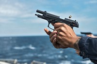 U.S. Navy Seaman Matthew Scott fires an M9 service pistol during a small arms weapons qualification course on the flight deck aboard the Ticonderoga-class guided-missile cruiser USS Chancellorsville (CG 62) as part of Invincible Spirit 2016 in the waters surrounding the Korean Peninsula, Oct. 12, 2016.