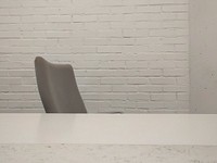 White wall with gray chair. Free public domain CC0 photo.