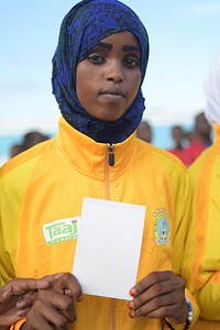 A Somalia lady holds a white card as a symbol of peace, at a ceremony to mark International Sports Day for development and peace in Mogadishu on April 06, 2017. UN Photo / Ilyas Ahmed. Original public domain image from Flickr