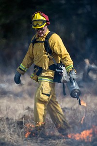 U.S. Air Force Senior Airman Grant Kopplin, a fire protection specialist assigned to the 673d Civil Engineer Squadron, uses a drip torch to light a back fire during a controlled burn at the Infantry Platoon Battle Course on Joint Base Elmendorf-Richardson, Alaska, May 5, 2017. Controlled burns consume accumulated dry brush and grass thereby reducing the risk of wildfires. Kopplin is a native of Willard, Mo. (U.S. Air Force photo by Alejandro Pena). Original public domain image from Flickr