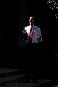 President Barack Obama stands in a shaft of light while playing football outside the Oval Office May 20, 2009.