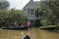 Marines with Charlie Company, 4th Reconnaissance Battalion, 4th Marine Division, Marine Forces Reserve, along with a member of the Texas Highway Patrol and Texas State Guard, patrol past a flooded house in Houston, Texas, Aug. 31, 2017.
