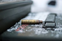 An expended 5.56mm casing rests on an ammunition can as Airmen assigned to the 673d Security Forces Squadron conduct an M249 Squad Automatic Weapon, and M2 .50 Caliber machine gun qualification range on Joint Base Elmendorf-Richardson, Alaska, Jan. 10, 2018. Security Forces Airmen perform extensive training in law enforcement as well as combat tactics to protect U.S. Military bases and assets both stateside and overseas. (U.S. Air Force photo/Justin Connaher). Original public domain image from Flickr