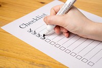 Side view of a hand writing on a checklist on the wooden surface