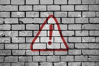 Caution sign on brick wall. Free public domain CC0 photo.