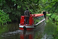 Person standing on red boat. Free public domain CC0 photo.
