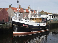 Black fishing boat at dock. Free public domain CC0 photo.