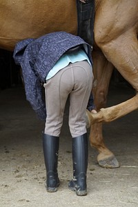 Girl cleaning horse hoof. Free public domain CC0 photo.