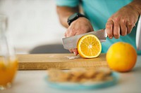Free cose up of male hands cutting orange on chopping board in the kitchen image, public domain fruit CC0 photo.