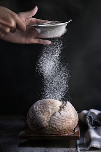 Free baker after baking fresh bread sprinkles sugar powder on bread with a cup powder flour sieve image, public domain food CC0 photo.