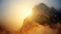 View of mountain range covered in fog with yellow sunlight