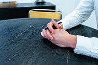 Close up of unrecognizable person folded hands with pen on the office desk