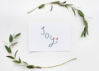 Card with a text Joy in a green plant decoration