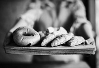Closeup of hands holding fresh baked bread on wooden tray