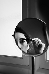 Woman applying makeup using a mirror