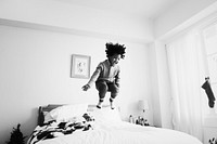 African kid having a fun time jumping on the bed