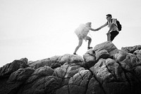 Friends helping each other up a mountain