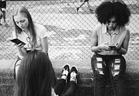 Friends using smartphones in a park