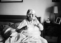 Senior woman taking medicine in bed