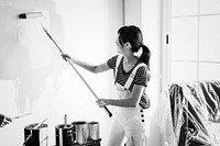 Asian woman painting the house wall