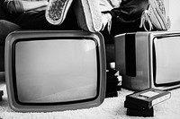 Two men putting legs on retro televisions