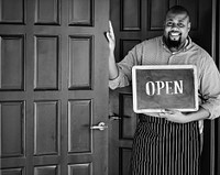 A cheerful small business owner with open sign