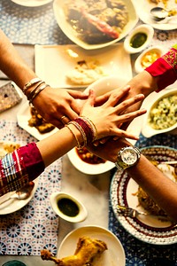 Group of Indian friends stacking hands over food