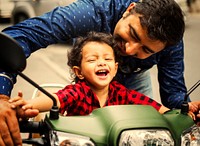 Indian father and son playing on a motorbike