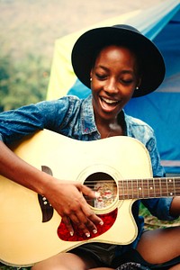 Woman playing guitar at a campsite
