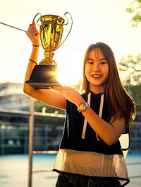 Asian teenage girl holding up a trophy