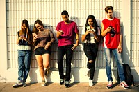Young teenage friends chilling out together and using smartphones