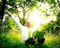 Businessman sitting in a forest with his laptop