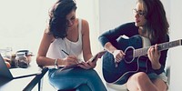 Lesbian couple playing guitar in their home