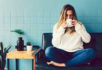 Girl drinking coffee by a blue wall