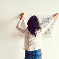 Woman putting up a blueprint on the wall