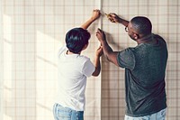 Couple decorating putting up a wallpaper