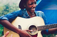 African American woman playing a guitar at a campsite