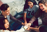 Group of teenagers in a bedroom putting their hands together