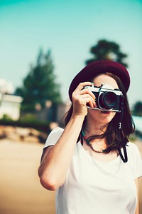 Girl in hat taking photos with a vintage camera