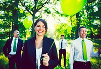 Business people holding a green balloon in the forest