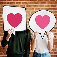 Young couple holding speech bubbles with heart icons