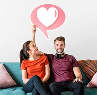 Cheerful couple holding a speech bubble with heart icon