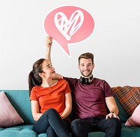 Cheerful couple holding a speech bubble with heart icon