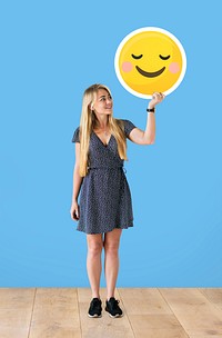 Cheerful woman holding a blushing emoticon