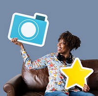 Cheerful woman showing blue camera icon on couch